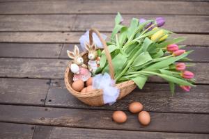 una cesta de huevos de Pascua y flores sobre una mesa de madera en Horizont Panzio, en Odorheiu Secuiesc