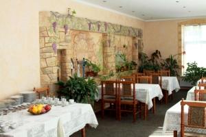 a dining room with tables and a wall with a mural at Edem Hotel in Chişinău