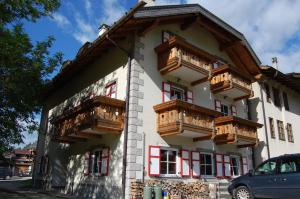 - un bâtiment avec des balcons en bois sur le côté dans l'établissement Appartamenti Casari, à Pozza di Fassa