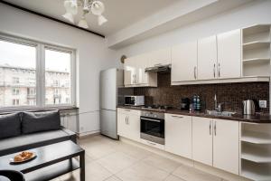 a kitchen with white cabinets and a couch at Apartamenty Wawa Centrum by Your Freedom in Warsaw