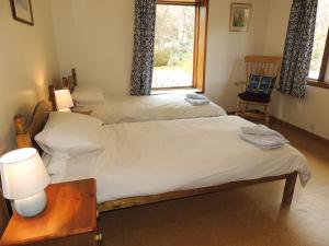 twee bedden in een kamer met een tafel en een raam bij Atlantic Bay Cottage in Clachan