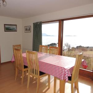 a dining room with a table and chairs and a window at Atlantic Bay Cottage in Clachan