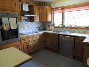 a kitchen with wooden cabinets and a sink and a window at Atlantic Bay Cottage in Clachan +3 photos