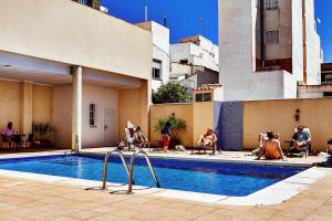 a group of people sitting around a swimming pool at Mi Patio in Torrevieja