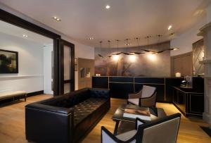 a living room with a black leather couch and chairs at Nottingham Place Hotel in London