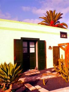 a white building with green doors and a palm tree at La Finca Uga in Uga