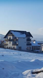 Un grand bâtiment blanc avec de la neige au sol dans l'établissement Casa Dar&And, à Vatra Dornei