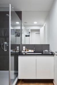 a kitchen with white cabinets and a glass shower at The Doorman Welle Frankfurt am Main in Frankfurt/Main