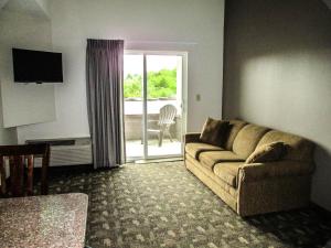 sala de estar con sofá y puerta corredera de cristal en Crystal Springs Inn and Suites en Towanda