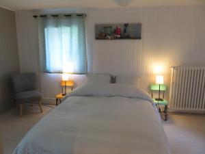 a bedroom with a large white bed with two lamps at Chambres d'hôtes - B&B in Gétigné +3 photos