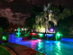 a pool lit up at night with colorful lights at Hotel Carmen in Puerto Iguazú
