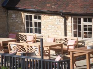 un groupe de tables et de chaises en bois devant un bâtiment dans l'établissement Bear and Ragged Staff, à Oxford