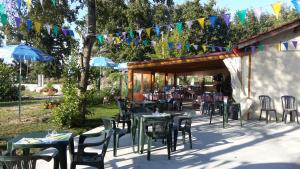 un patio al aire libre con mesas, sillas y sombrillas en Paradis Des Dombes, en Sandrans
