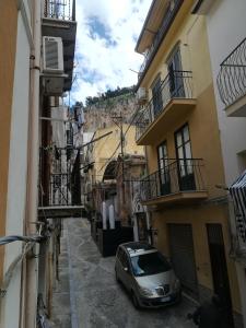 Un coche aparcado en un callejón entre dos edificios. en amendola24, en Cefalú