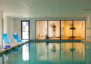 a swimming pool with a man standing in a room at Goélia Les 7 Iles in Perros-Guirec
