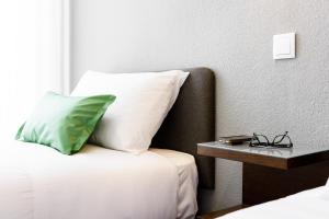 uma cama com uma almofada e uma mesa lateral em Hotel Portuense Lisboa em Lisboa