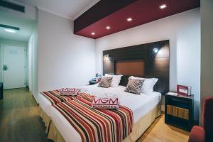フンシャルにあるMuthu Raga Madeira Hotelのベッドルーム(白い大型ベッド、ストライプ毛布付)