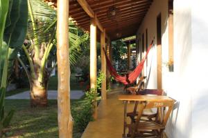 a porch with a hammock and a table and chairs at Family Guest House in Ilha de Boipeba
