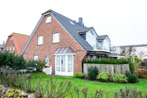 a red brick house with a fence in the yard at App-Syltperle in Westerland (Sylt)