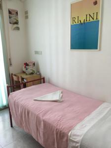 a room with a bed with a pink blanket and a table at Hotel Peonia in Rimini +21 photos