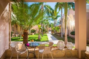 a patio with a table and chairs and palm trees at Danaides in Malia