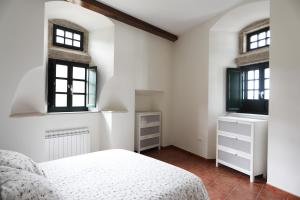 a white bedroom with two windows and a bed at Casa Pedrosa in Mondoñedo