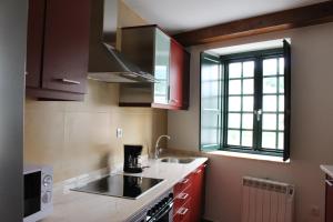 cocina con armarios rojos, fregadero y ventana en Casa Pedrosa, en Mondoñedo
