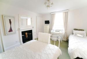 1 dormitorio blanco con 2 camas y chimenea en No 4 Ainslie's Belvedere B&B, en Bath