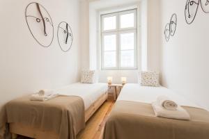 two beds in a room with white walls and windows at Baixa Modern Three-Bedroom Apartment - by LU Holidays in Lisbon