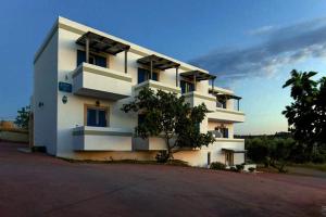 a white building with a tree in front of it at Contaratos Holiday Lettings 3 in Livadi