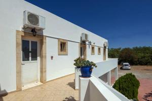 a white house with a potted plant on a balcony at Contaratos Holiday Lettings 3 in Livadi