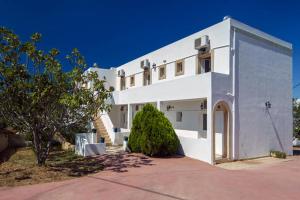 a large white building with a tree in front of it at Contaratos Holiday Lettings 3 in Livadi