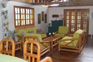 un soggiorno con sedie verdi, tavoli e finestre di Hotel Villa Carolina a Santa Rosa de Cabal
