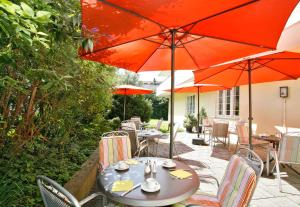 a table and chairs with umbrellas on a patio at Hotel Biederstein am Englischen Garten in Munich