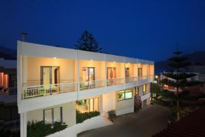 a white building with a balcony at night at Sofia Hotel in Plakias