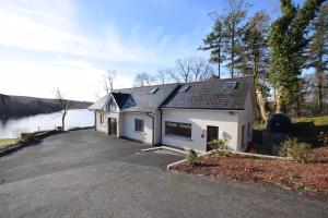 una casa bianca con un vialetto d'accesso accanto a un lago di Inishclare Cottages a Killadeas