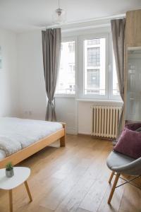 um quarto com uma cama, uma cadeira e uma janela em Bardolino Apartment em Belgrado