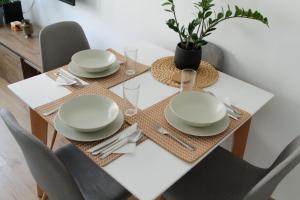a dining room table with white plates and silverware at Bardolino Apartment in Belgrade