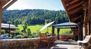 a patio with a table and chairs and an umbrella at Chalet le 1791 in La Clusaz