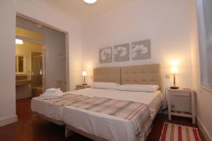 a white bedroom with a bed and two pictures on the wall at Apartamentos Madrid Retiro in Madrid