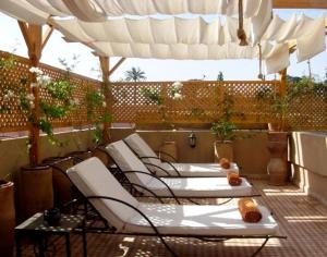 a row of lounge chairs on a patio with an umbrella at Riad Aderbaz in Marrakech