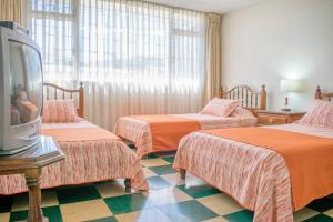 ein Hotelzimmer mit 3 Betten und einem Flachbild-TV in der Unterkunft GHL casa hotel in Bogotá