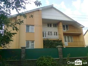 a large house with a green fence in front of it at Domashnya Saduba in Mukacheve
