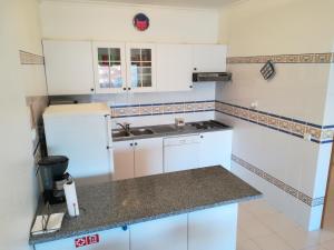 
a kitchen with white cabinets and white appliances at Apartamento Varandas do Sol Nascente in Porches
