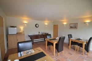 a living room with tables and chairs and a kitchen at Jex Farmhouse B&B in Little Snoring