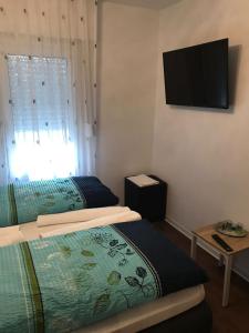 a bedroom with two beds and a television on the wall at Hotel-Restaurant Haus Nattkemper in Hamm