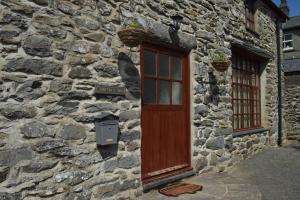a stone building with a wooden door and two windows at Stabl yr Nant in Pentrefoelas