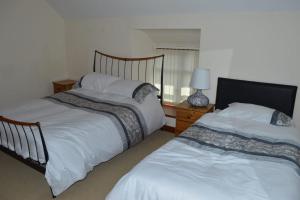1 dormitorio con 2 camas y mesa con lámpara en Stabl yr Nant en Pentrefoelas