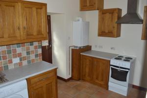 a kitchen with wooden cabinets and a white stove top oven at Stabl yr Nant in Pentrefoelas