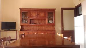 a dining room with a wooden table and a tv at Edelweiss in Palmi